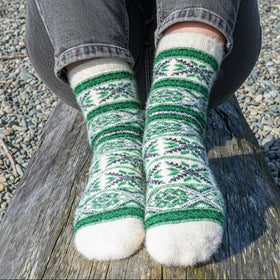 Person wearing patterned green and white socks on a wooden surface.