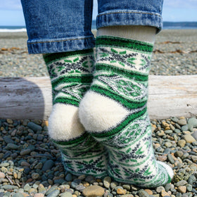 Green and white patterned socks worn on a rocky beach.