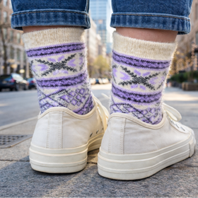 Person wearing white sneakers and patterned socks on a city street.