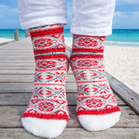 Red and white patterned socks worn on a wooden pier with ocean view