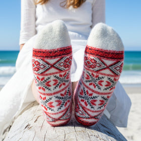 Person wearing red and white patterned socks on a beach