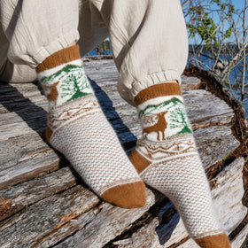Person wearing patterned socks with deer design on a snowy background