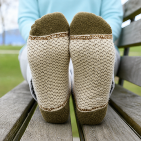 Person wearing patterned socks sitting on a wooden bench outdoors