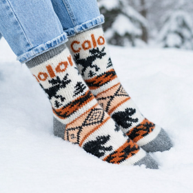 Person wearing patterned socks with 'Calo' branding in a snowy setting