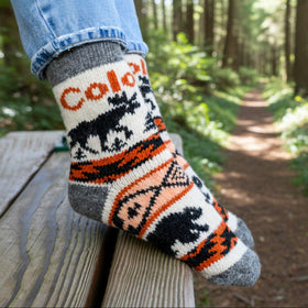 Person wearing a colorful sock with moose design in a forest setting
