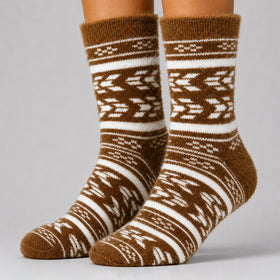 A pair of brown and off-white patterned crew socks worn on feet, shown against a neutral gray studio background.