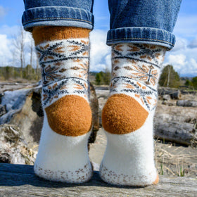 Person wearing patterned socks with brown and white design in a natural setting.