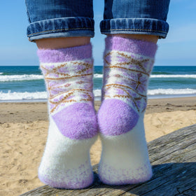 Person wearing patterned socks with a beach and ocean in the background