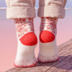 White socks with red polka dots worn by a person on a wooden surface with a blurred background