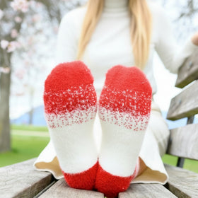 Red and white patterned socks worn by a person sitting on a bench outdoors.
