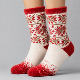 A pair of crew socks with a festive Fair Isle pattern in red, cream, and brown, shown on a model's feet against a neutral gray background.