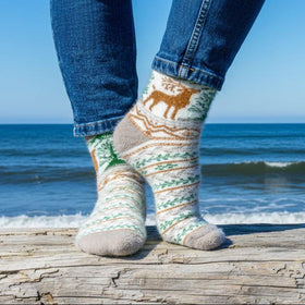 Person wearing patterned socks with a deer design by the ocean.