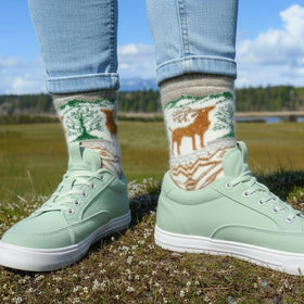 Person wearing green sneakers and patterned socks with a natural landscape in the background