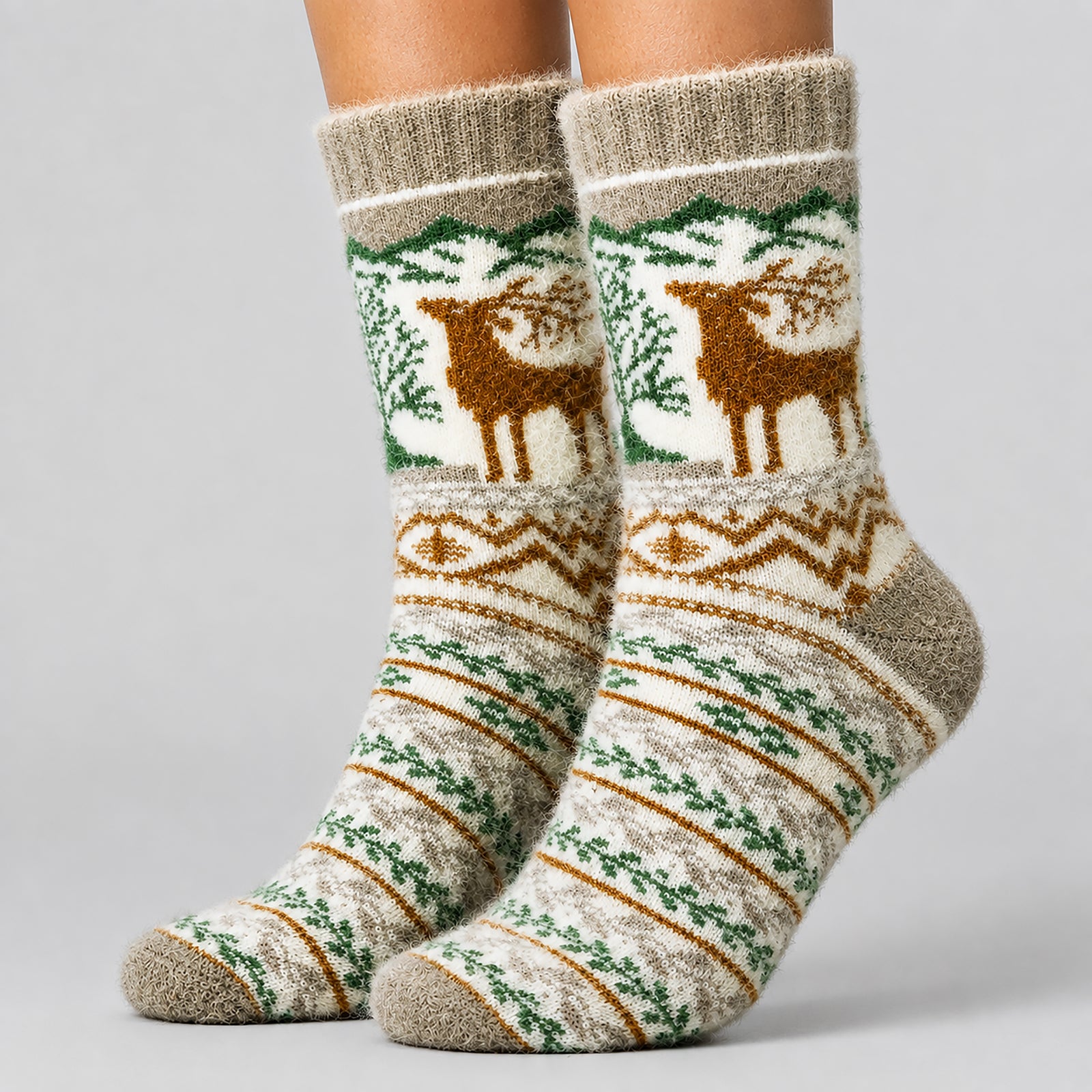 A pair of crew socks worn on feet, featuring a winter-themed knit pattern with brown reindeer, green trees, and geometric stripes on a cream and taupe background.