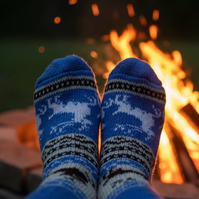 Blue patterned socks being worn by a person in front of a campfire.