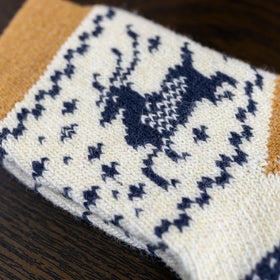 Knitted sock with blue deer pattern on a wooden surface