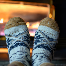 Pair of feet wearing patterned socks in front of a fireplace