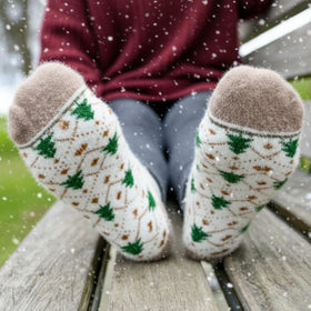 Person wearing patterned socks sitting on a bench in a snowy outdoor setting