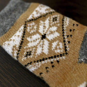 Close-up of a brown and gray patterned sock on a dark surface