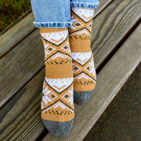 Patterned socks with mustard yellow, white, and gray design on a wooden surface.