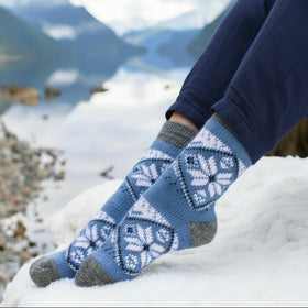 Person wearing blue patterned socks with a snowy landscape and mountains in the background
