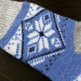 Knitted sock with blue and gray pattern on a wooden surface