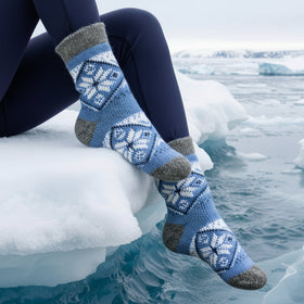 Person wearing blue patterned socks with gray toes and heels, sitting on ice.
