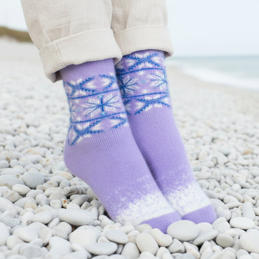 Person wearing purple socks with blue patterns on a pebbly surface