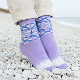 Person wearing purple socks with blue patterns on a pebbly surface