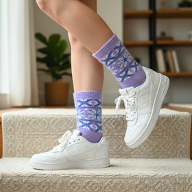 Person wearing white sneakers and purple patterned socks on a staircase.