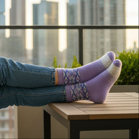Woman sitting on a rooftop with a city skyline view, holding a cup.