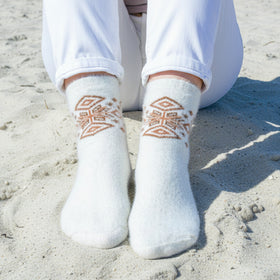 White socks with geometric patterns worn on a sandy surface