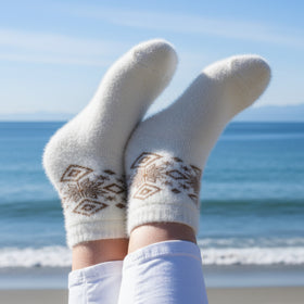 White socks with brown patterns on a beach with ocean view