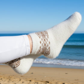 White socks with brown patterns on a beach with ocean in the background