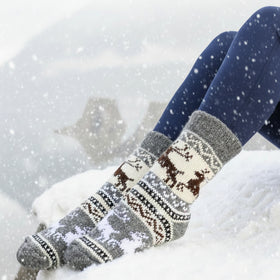 Person wearing patterned socks with a scenic background of water and mountains.